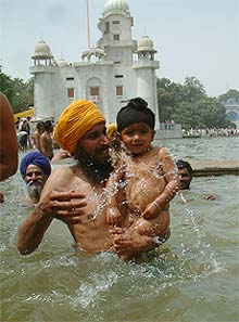 A young boy takes a holy bath along with his father at the sarovar at Talwandi Sabo on the occasion of Baisakhi on Monday