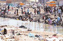Iraqi people take water from a polluted area for household needs in Basra, southern Iraq
