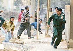 A policeman runs after being disarmed by a mob