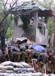 Security forces personnel stand near the damaged gate and security post of Radio Kashmir after an explosion in Srinagar on Saturday.