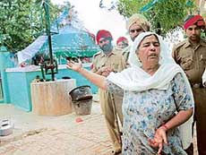 Iqbal Bibi, the sole caretaker of the Pir Baba Fateh Shah Qadir mazaar, points at the tomb and the place from where the violence triggered on June 5 at Talhan village in Jalandhar.