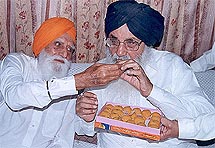 Mr Gurcharan Singh Tohra offers a "laddoo to Mr Parkash Singh