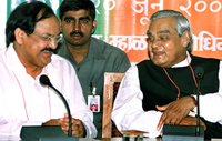 Prime Minister Atal Bihari Vajpayee laughs while sitting besides BJP President Venkaiah Naidu