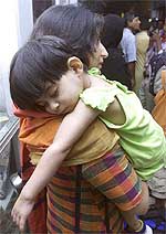 A Pakistani woman carries her sick two-and-a-half-year-old daughter 