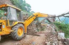 An earth mover clears the site of landslide