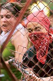 An anti-globalisation protester tries to remove a fence put up by the police at the entrance to the hotel of Cancun