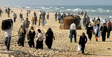 Palestinians walk along the Gaza beach after Israel sealed off the coastal road linking north and central parts of the Gaza Strip