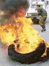 A policeman runs past burning tyres during a protest against the arrest of separatist leaders