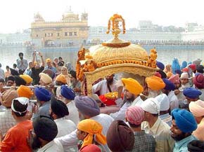 Devotees carry the palki of Guru Granth Sahib in the Golden Temple on the eve of the birth anniversary of Guru Nanak Dev in Amritsar