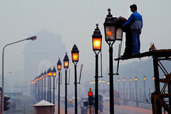 Workers fix a streetlight during a foggy day in New Delhi. Fog returned to the capital on Wednesday with the minimum temperature around 12°C.