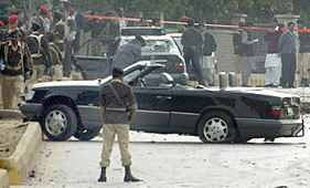 Pakistani soldiers stand guard near damaged cars at the site of suicide bomb attacks on President Pervez Musharrafs motorcade in Rawalpindi on Thursday.