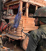 Troops stand near the damaged bus after a landmine explosion 