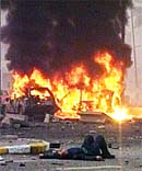 An injured Iraqi man lies on the road near the wreckage after a car bomb attack 