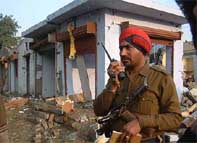 A policeman stands near damaged buildings after a bomb blast in the Amritsar District Courts complex 