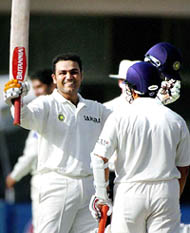 Virender Sehwag raises his bat and helmet after reaching a double century during the first day of the first Test between Pakistan and India in Multan on Sunday.