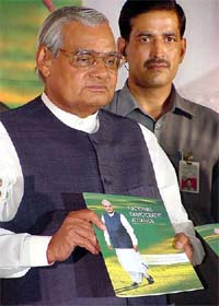 Prime Minister Atal Bihari Vajpayee poses with a copy of the National Democratic Alliance (NDA) manifesto after its release in Delhi