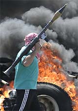 An Iraqi insurgent walks past a blazing vehicle