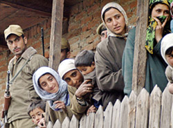 Policemen stand guard as Kashmiri women watch an election campaign rally by the Peoples Democratic Party (PDP) in Surasyar, 40 km west of Srinagar