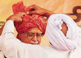 A BJP worker helps Deputy Prime Minister L. K. Advani wear a traditional turban during an election meeting at Najafgarh