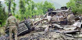Paramilitary forces search the debris of a bus blown up by militants at Lower Munda on the Jammu-Kashmir highway on Sunday.