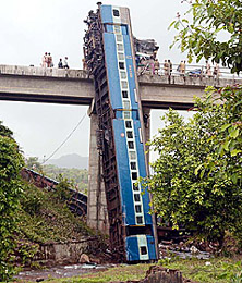 Derailed coaches of the Mumbai-bound Matsyagandha Express passenger train hang from a bridge at Amboli village, 200 km from Mumbai, on Wednesday