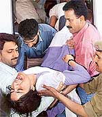 A Kashmiri woman, wounded in a grenade blast in Srinagar, is taken out from an ambulance