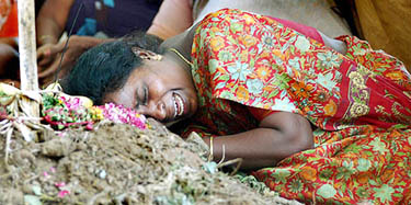 A woman relative cries over the grave of a girl