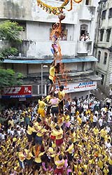 Curd flows as the top person of a human pyramid breaks a curd pot hung from a decorated rope between buildings on the occasion of Krishna Janmashtami, the birth anniversary of Lord Krishna, in Mumbai 