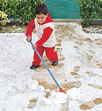 A Kashmiri boy removes snow from his garden in Srinagar on Tuesday. Srinagar witnessed the seasons first snowfall on Tuesday.