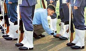 An attendant gives a last-minute touch on the shoes of a soldier on the occasion of the 34th Navy Day celebrations at Amar Jawan Jyoti in New Delhi