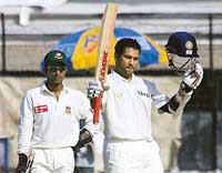 Sachin Tendulkar raises his bat and helmet after completing his double century against Bangladesh, as wicketkeeper Khaled Mashud looks on, during the third day of the first Test in Dhaka on Sunday.