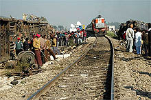 Mangled remains of the damaged coaches of two trains lie on either side as a train runs on the track near Mukerian on Wednesday.