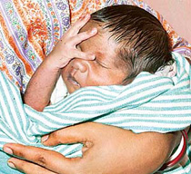 Six-day-old Tsunami Roy, sleeps in his mothers arms at a relief camp at Port Blair