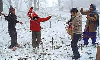 Tourists enjoy the snowfall at Kasauli on Saturday.