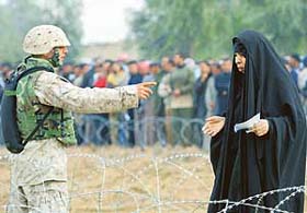 A US Marine gestures to an Iraqi woman outside a voting centre in Al Anbar province, 23 km west of Baghdad