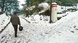 A man walks on fresh snow in Shimla on Monday. 