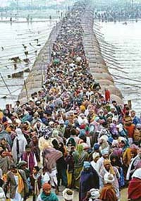 Pilgrims walk across a pontoon bridge to take a holy dip in the Ganga during Magh Mela in Allahabad
