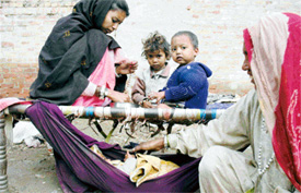 A mother makes ornaments using semi-precious stones while the children’s grandmother looks after the baby in the improvised hammock