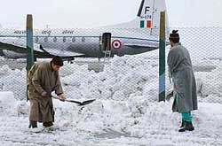 Labourers clear snow at the Srinagar airfield to enable airlift operations