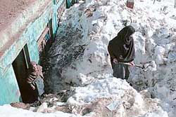 A woman removes snow in front of her hut in Batote, 120 km north of Jammu, on Friday.