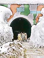 People walk towards the snow-covered northern portal of Jawahar Tunnel, 90 km south of Srinagar, on Tuesday.