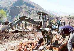 Workers repair the Uri-Muzaffarabad road near the Kaman post, 127 km from Srinagar, on the LoC on Sunday.