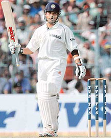 Sachin Tendulkar raises his bat to acknowledge the crowd after completing his 10,000 runs during the first day of the second India-Pakistan Test match in Kolkata on Wednesday.