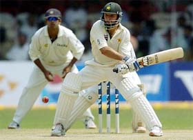 Pakistans Shahid Afridi plays a reverse sweep as Indias Rahul Dravid looks on during the fourth days play of the third Test match between India and Pakistan in Bangalore