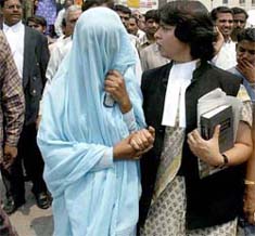 A lawyer escorts the rape victim (face covered) after a hearing at a court in New Delhi