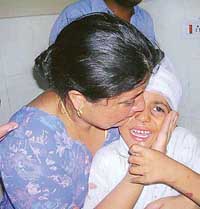 A mother consoles her child who was injured when a school van was hit by a speeding Tata Sumo