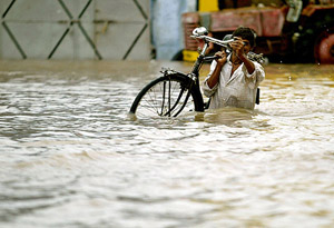 A man carries his bicycle through a flooded street in Dhandhuka town, 105 km west of Ahmedabad, on Thursday.