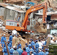 Rescue workers watch as a mechanical digger removes rubble from a landslide to search for survivors in the Saki Naka suburb of Mumbai on Thursday.