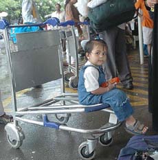 A child rests on a luggage trolley as passengers are stranded at the airport in Mumbai after air service was suspended due to heavy rain on Sunday.