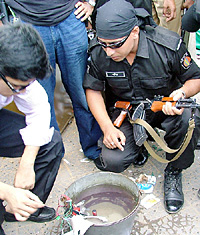 Two members of the Rapid Action Battalion (RAB) of the Bangladeshi Special Security Force take a close look at an explosive device, following a series of blasts, in Chittagong